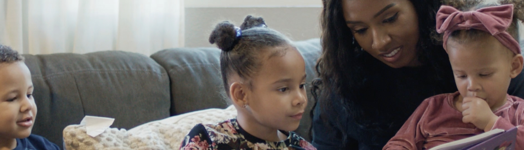 An African American adoptive mom reads to three young siblings